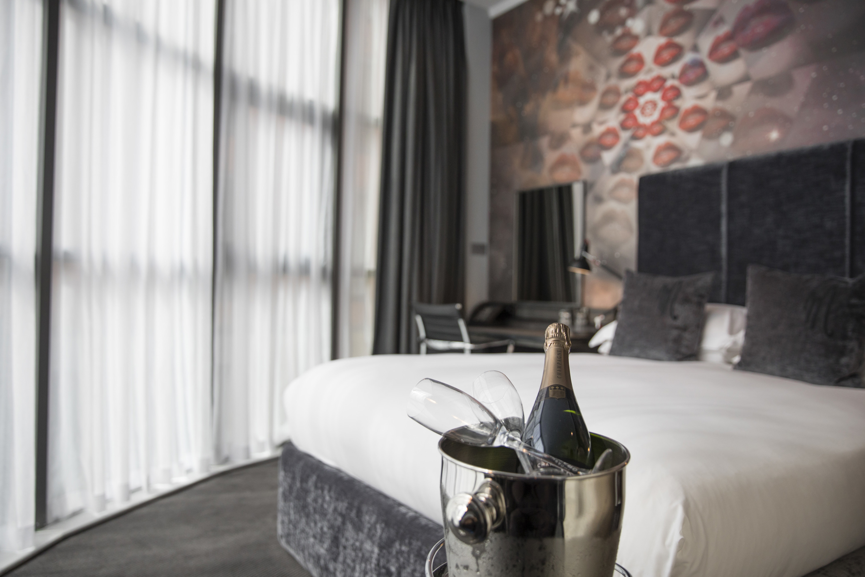 Champagne and two glasses in front of a bed