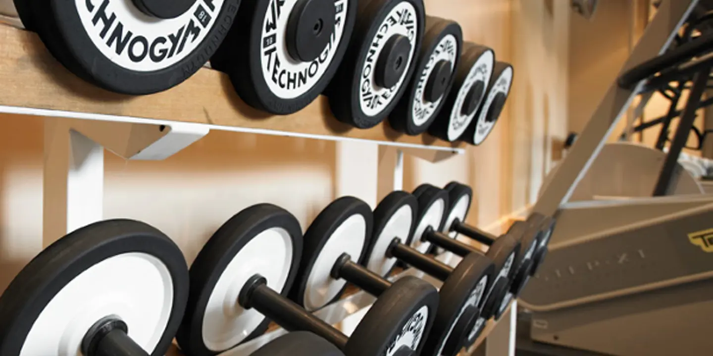Interior of a gym with a close up of free weights and treadmills