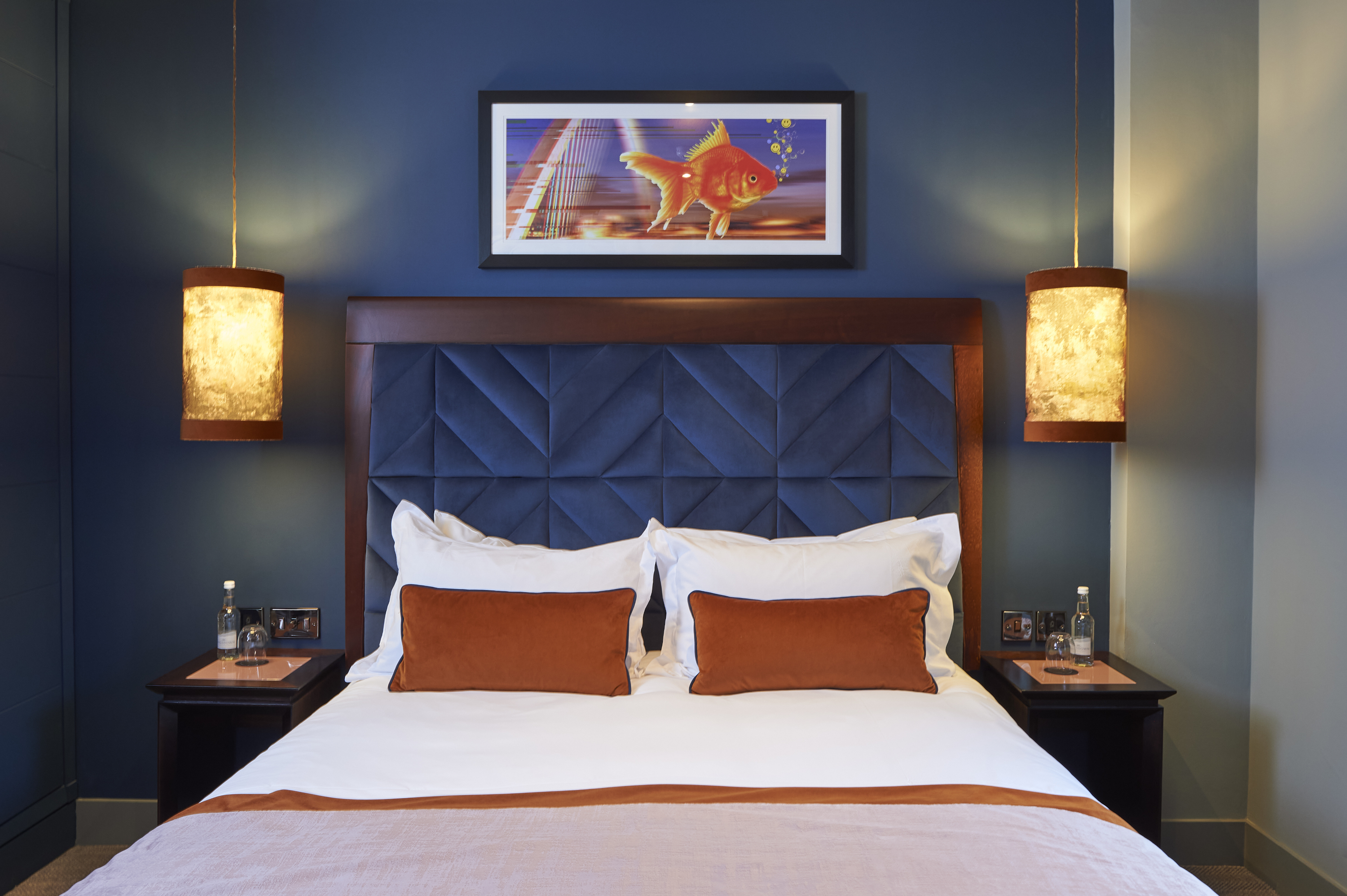 A bed featuring a stylish blue headboard adorned with vibrant orange pillows.