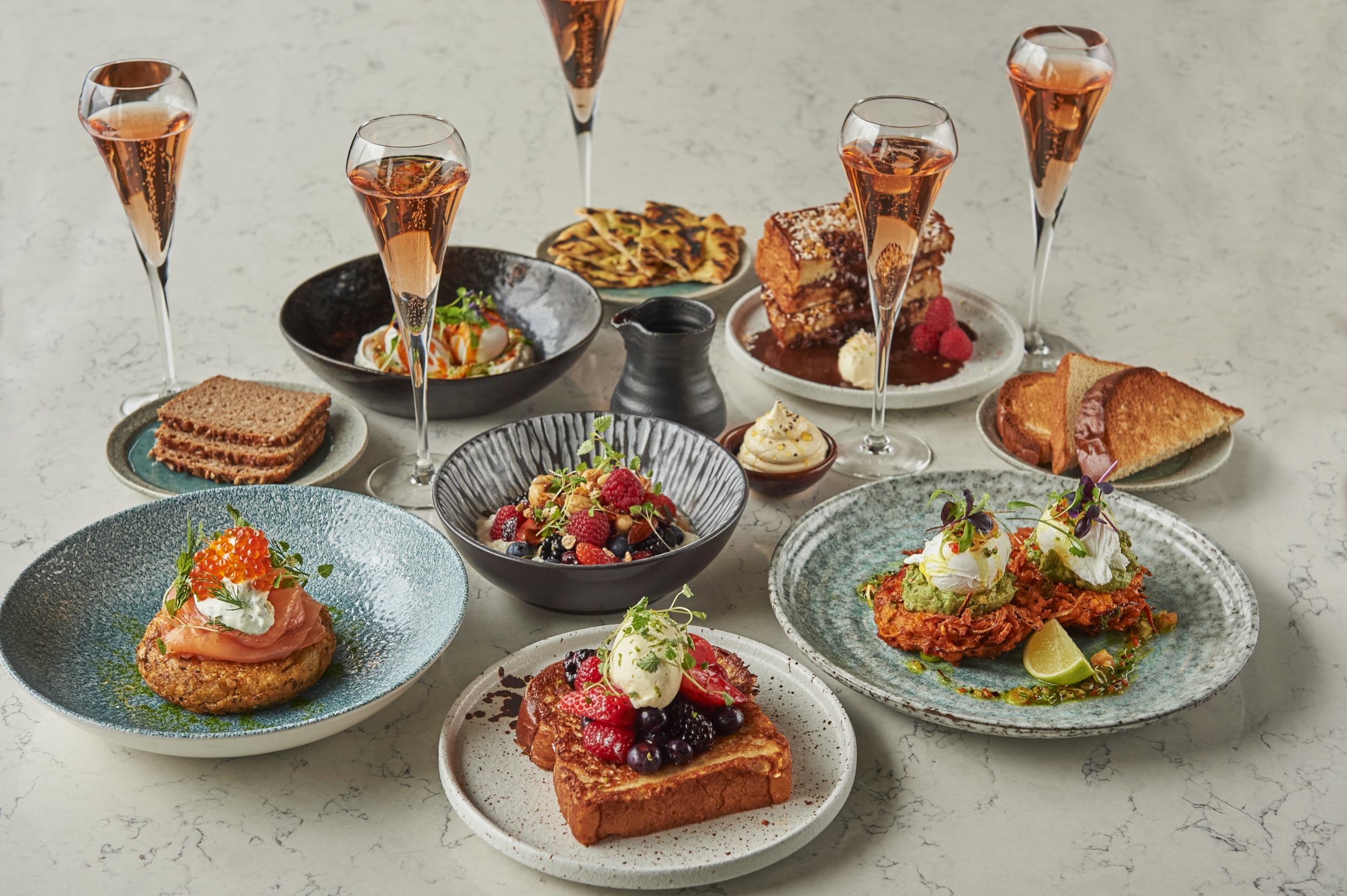 A table adorned with plates of delectable cuisine and elegant champagne glasses.