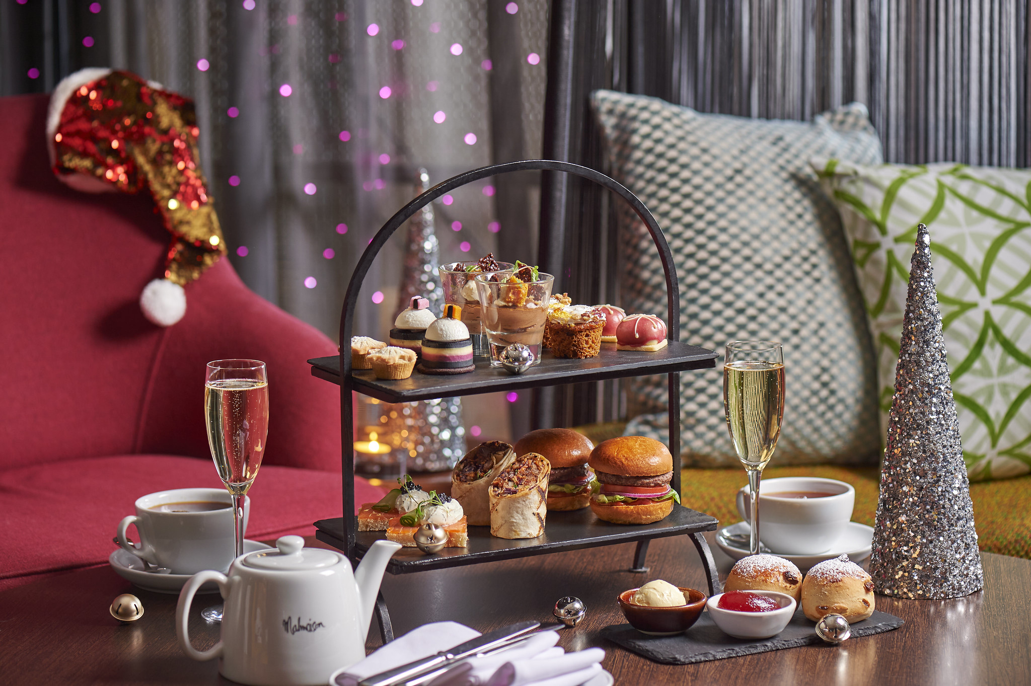 A table displaying a tray of appetizing food accompanied by a glass of fine wine and Christmas decorations in the background.